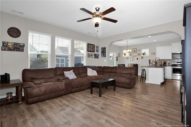 living room featuring hardwood / wood-style flooring, sink, and ceiling fan with notable chandelier