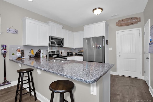 kitchen featuring white cabinetry, appliances with stainless steel finishes, decorative backsplash, and kitchen peninsula