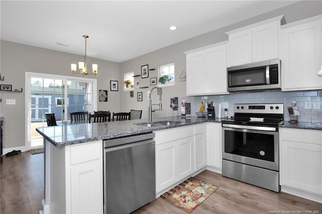 kitchen featuring sink, appliances with stainless steel finishes, hanging light fixtures, white cabinets, and kitchen peninsula