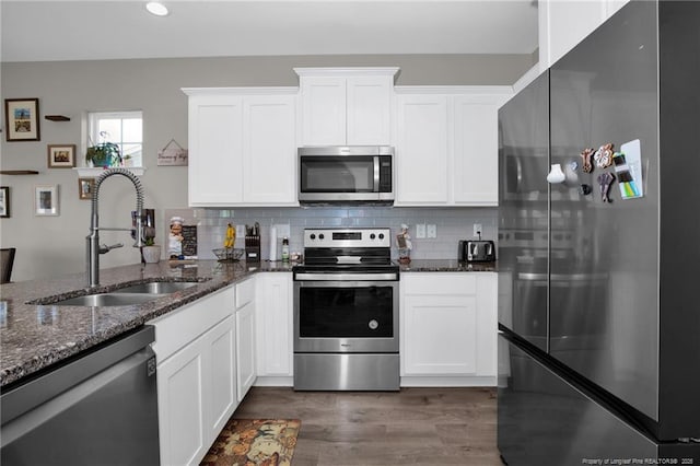 kitchen featuring white cabinetry, sink, dark stone counters, and appliances with stainless steel finishes