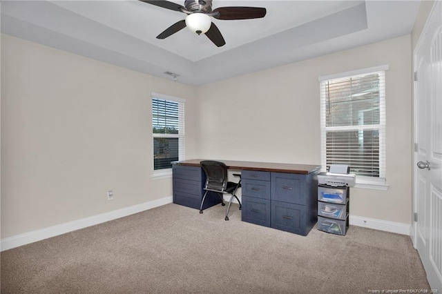 carpeted office space featuring ceiling fan and a raised ceiling