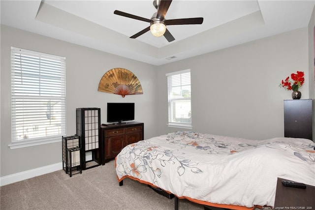 carpeted bedroom featuring ceiling fan and a raised ceiling