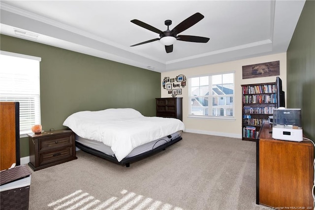 carpeted bedroom with crown molding, ceiling fan, and a tray ceiling