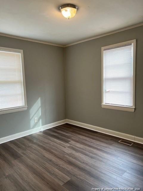 unfurnished room with dark wood-type flooring, ornamental molding, and plenty of natural light