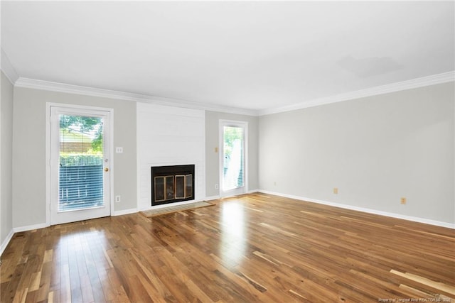 unfurnished living room featuring crown molding, a wealth of natural light, a large fireplace, and hardwood / wood-style flooring