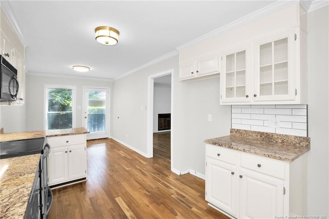 kitchen with dark hardwood / wood-style floors, tasteful backsplash, white cabinets, ornamental molding, and light stone countertops