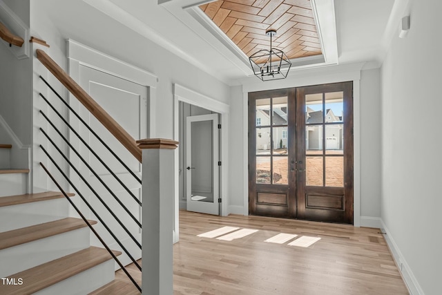 doorway to outside featuring french doors, light hardwood / wood-style floors, and a tray ceiling