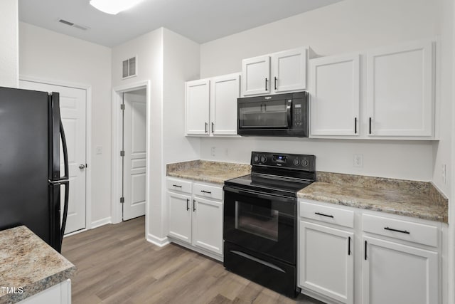 kitchen with white cabinetry, light stone counters, black appliances, and light wood-type flooring