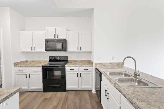 kitchen featuring hardwood / wood-style flooring, white cabinetry, sink, and black appliances