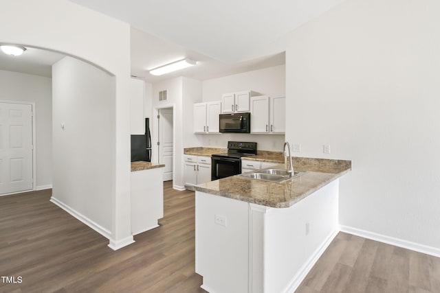 kitchen with black appliances, white cabinetry, sink, hardwood / wood-style flooring, and kitchen peninsula