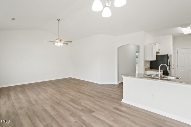 kitchen with lofted ceiling, sink, ceiling fan, white cabinetry, and black refrigerator