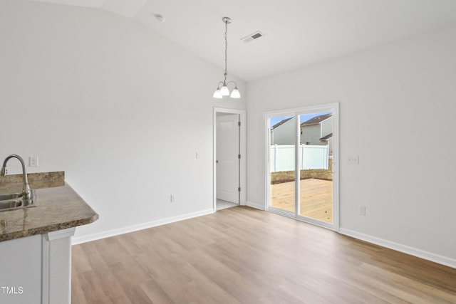 unfurnished dining area with vaulted ceiling, an inviting chandelier, sink, and light hardwood / wood-style flooring