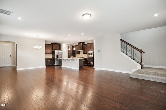 unfurnished living room featuring dark wood-type flooring, sink, and a notable chandelier