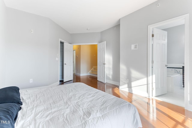 bedroom with ensuite bathroom and hardwood / wood-style floors