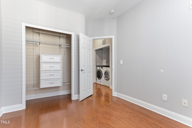 laundry area featuring cabinets, washer and clothes dryer, and hardwood / wood-style floors