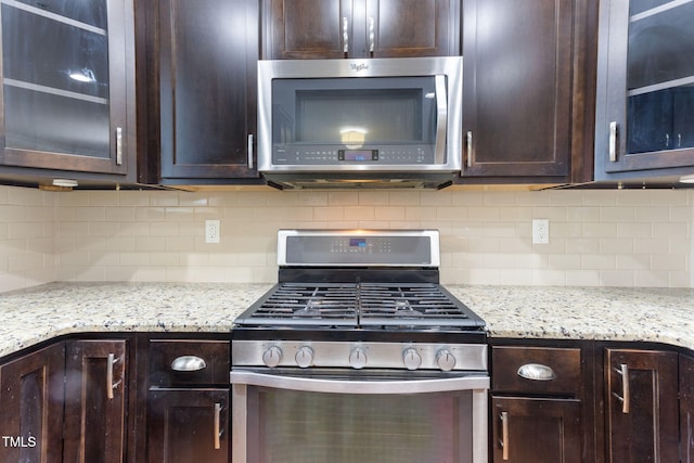 kitchen with tasteful backsplash, appliances with stainless steel finishes, and dark brown cabinets