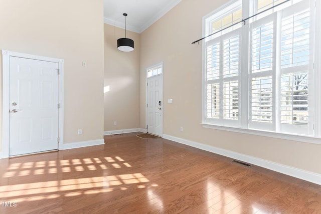 entrance foyer with hardwood / wood-style flooring, ornamental molding, a healthy amount of sunlight, and a high ceiling