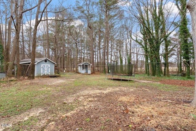 view of yard with a storage unit, a trampoline, an outdoor structure, and fence