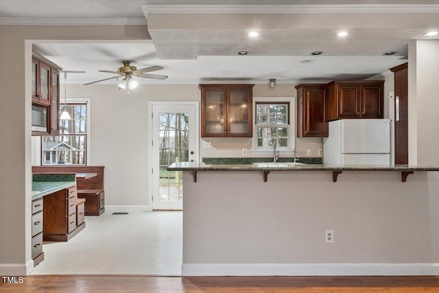 kitchen with a kitchen bar, light wood finished floors, dark stone counters, and freestanding refrigerator