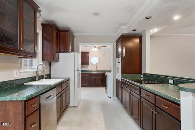 kitchen featuring white appliances, ornamental molding, dark countertops, and a sink