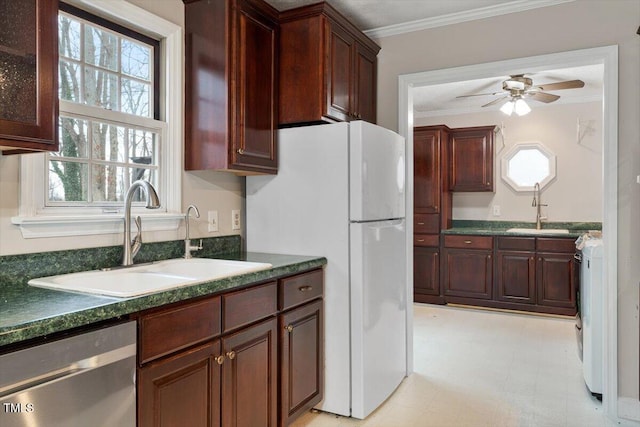 kitchen with dark countertops, light floors, dishwasher, ornamental molding, and a sink