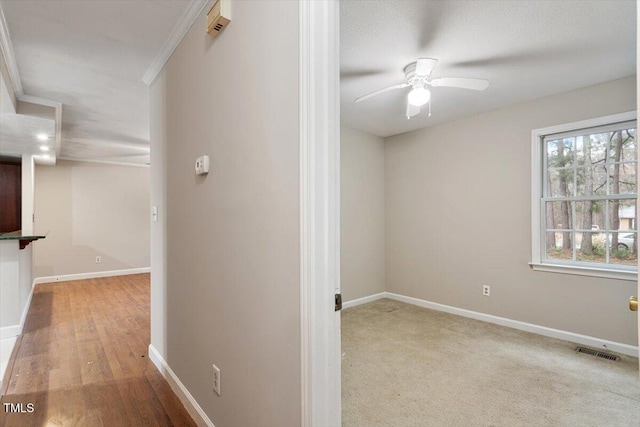 corridor featuring visible vents, baseboards, and crown molding