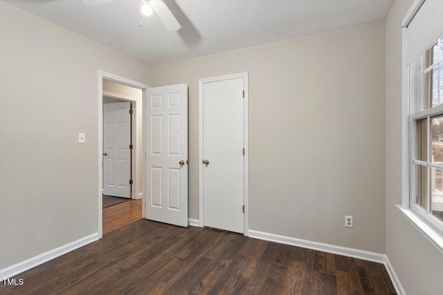 unfurnished bedroom with baseboards, dark wood-type flooring, and a ceiling fan