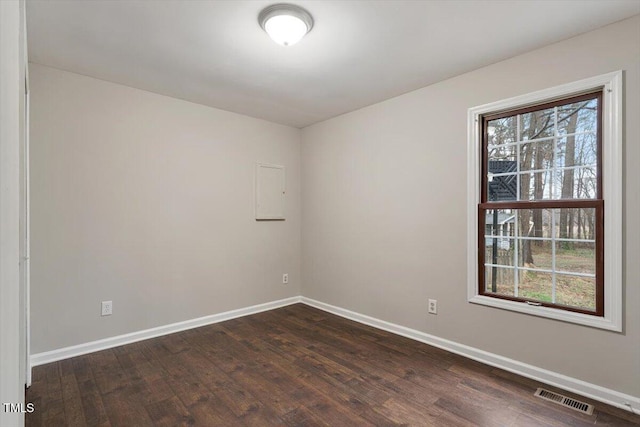 spare room featuring visible vents, dark wood-type flooring, and baseboards