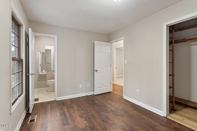 unfurnished bedroom featuring baseboards, visible vents, hardwood / wood-style flooring, a closet, and connected bathroom