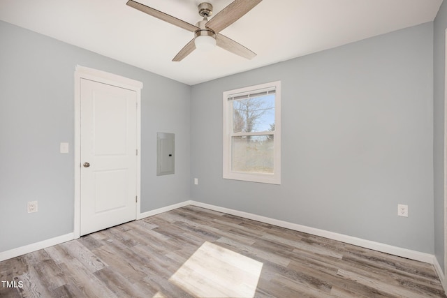 unfurnished room with ceiling fan, electric panel, and light hardwood / wood-style floors