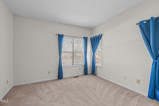 spare room featuring light carpet and a textured ceiling