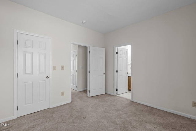 unfurnished bedroom featuring light colored carpet and ensuite bathroom