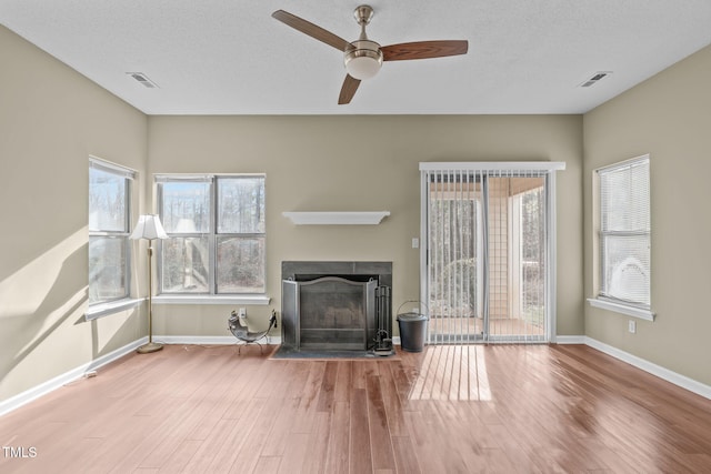 unfurnished living room featuring ceiling fan, a textured ceiling, and light hardwood / wood-style floors