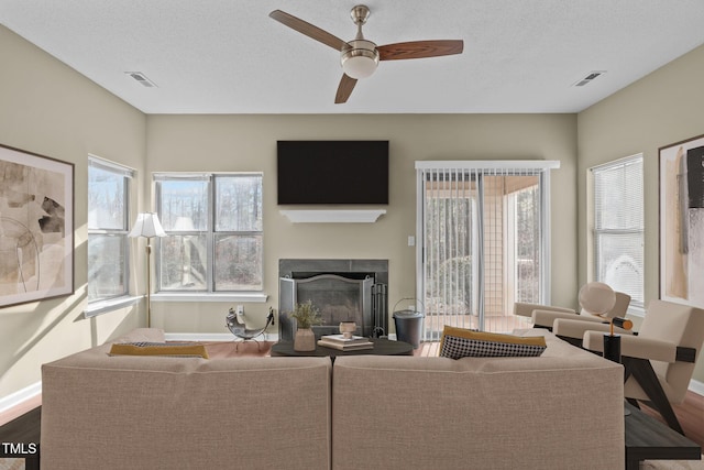 living room featuring a textured ceiling, wood-type flooring, and ceiling fan