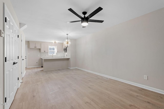 unfurnished living room featuring sink, ceiling fan with notable chandelier, and light hardwood / wood-style floors