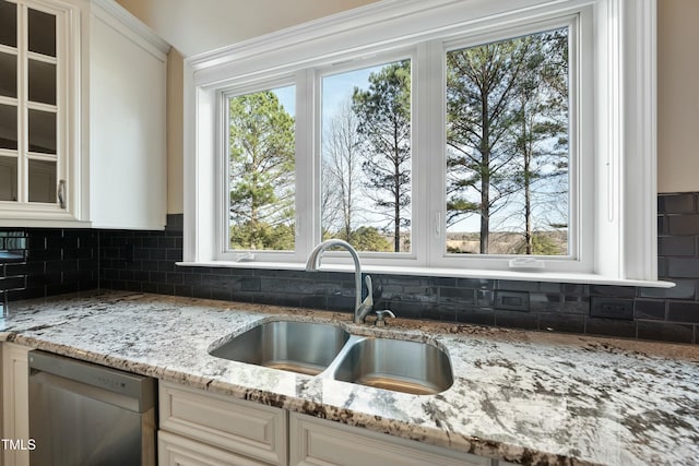 kitchen featuring light stone countertops, plenty of natural light, sink, backsplash, and dishwasher