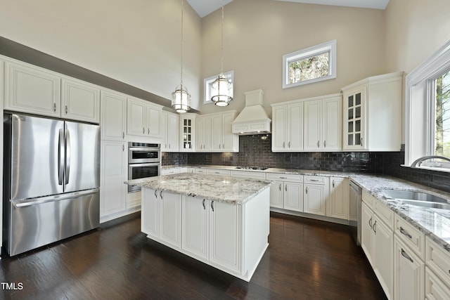 kitchen with stainless steel appliances, white cabinetry, a center island, sink, and custom exhaust hood