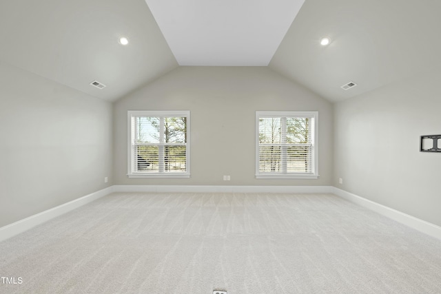 spare room with light carpet, plenty of natural light, and vaulted ceiling