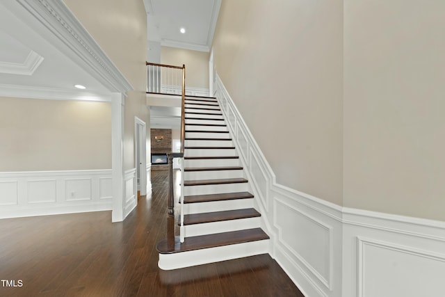 stairway with hardwood / wood-style flooring, crown molding, and a high ceiling