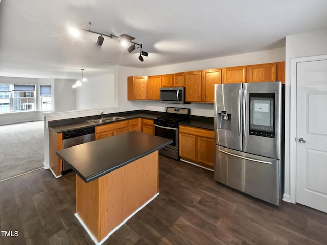 kitchen with sink, hanging light fixtures, stainless steel appliances, track lighting, and kitchen peninsula