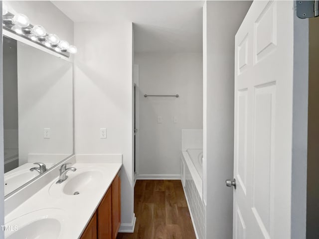 bathroom featuring vanity, hardwood / wood-style floors, and a tub to relax in