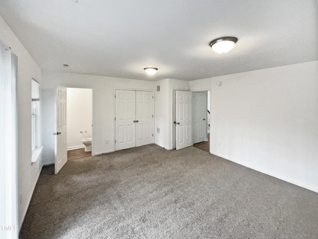 unfurnished bedroom featuring ensuite bath and dark carpet