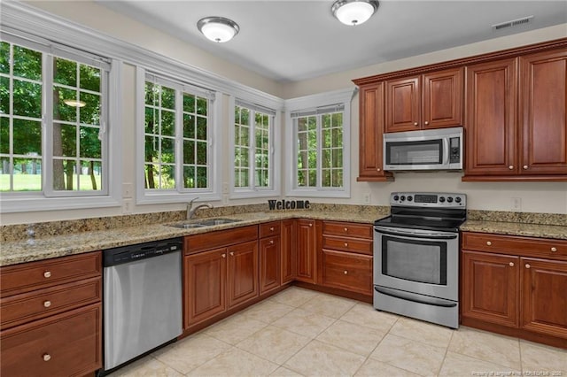 kitchen with light stone counters, appliances with stainless steel finishes, light tile patterned flooring, and sink