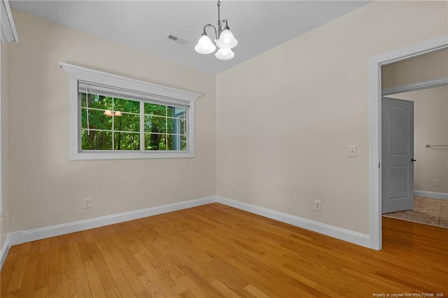 unfurnished room with a chandelier and light hardwood / wood-style flooring