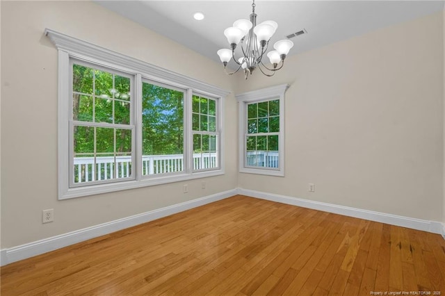 unfurnished room featuring a notable chandelier and light hardwood / wood-style floors