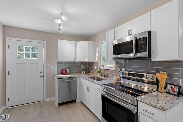 kitchen featuring stainless steel appliances, sink, white cabinets, and light wood-type flooring