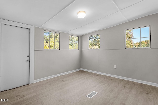 empty room featuring vaulted ceiling and light wood-type flooring