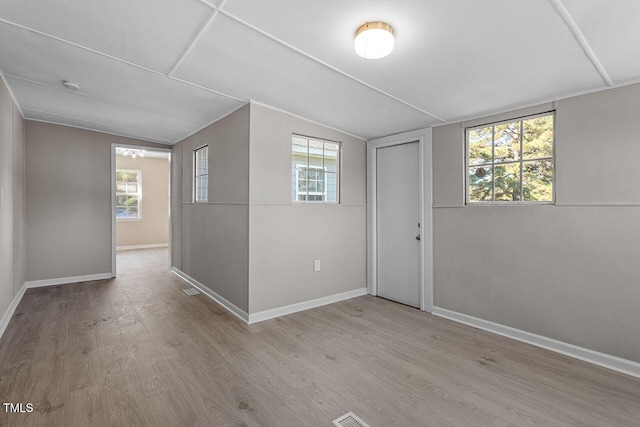 spare room featuring lofted ceiling and light wood-type flooring