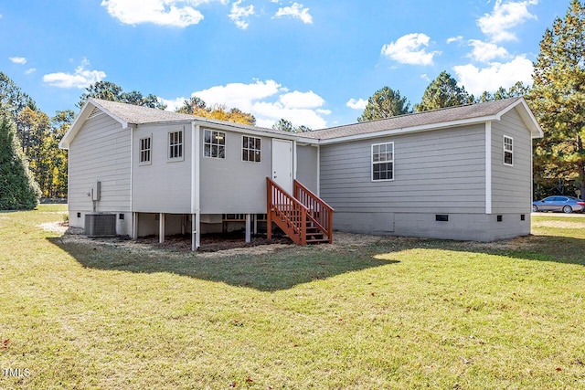 rear view of house with central AC and a lawn