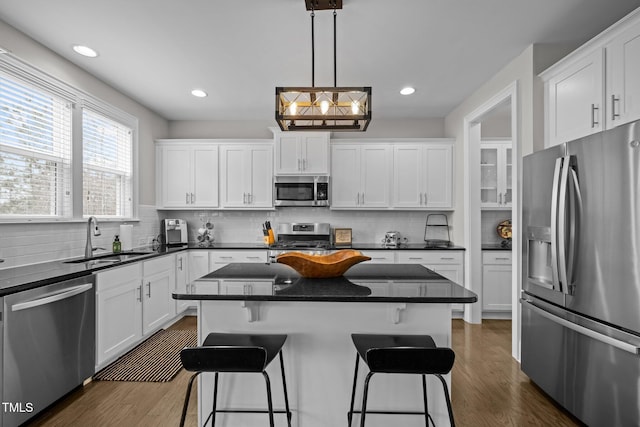 kitchen with stainless steel appliances, a center island, sink, and white cabinets